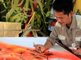 Artisant malaisien, dans son atelier de Kuala Lumpur, en train de peindre un Batik.